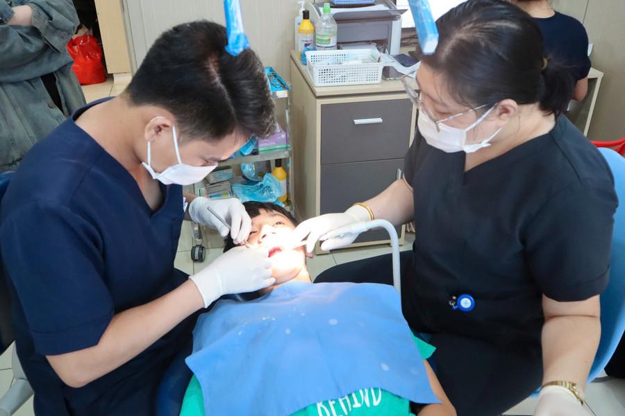 Các y, bác sĩ chăm sóc răng miệng cho trẻ bại não. (Ảnh: TT) 6-te.jpg