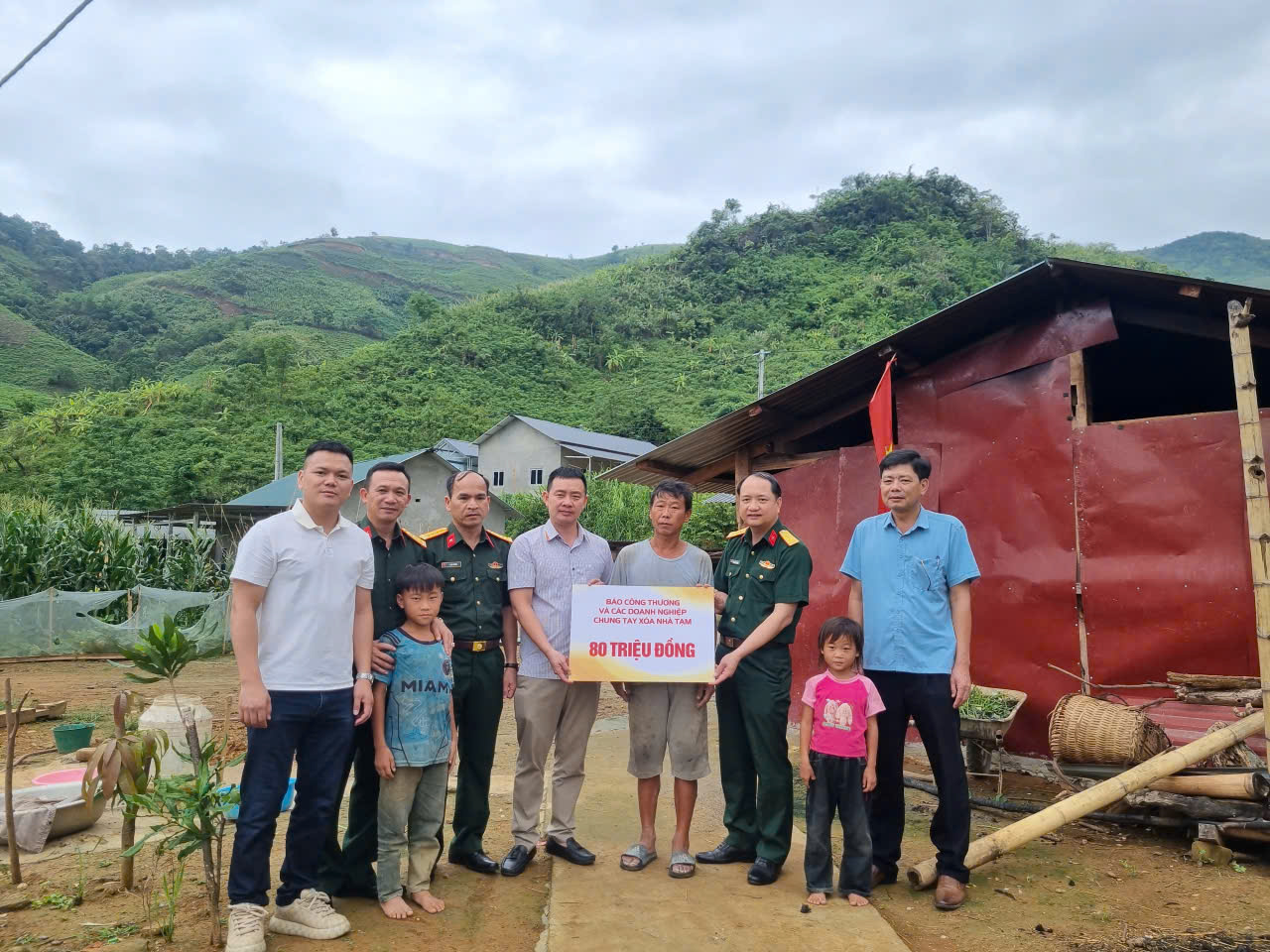 Đại diện Báo Công Thương phối hợp với Ban Chỉ huy Quân sự huyện Phong Thổ (cũ) và chính quyền xã Bản Lang trao biển tượng trưng 80 triệu đồng cho gia đình ông Tẩn A Lơ. Số tiền sau đó được chuyển cho Ban Chỉ huy Quân sự huyện để hỗ trợ xây dựng lại căn nhà bị sập do mưa lốc. Ảnh: Văn Thi