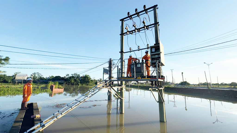 Lực lượng kỹ thuật kiểm tra, gia cố trạm biến áp giữa vùng ngập để duy trì vận hành an toàn trong mùa mưa lũ.