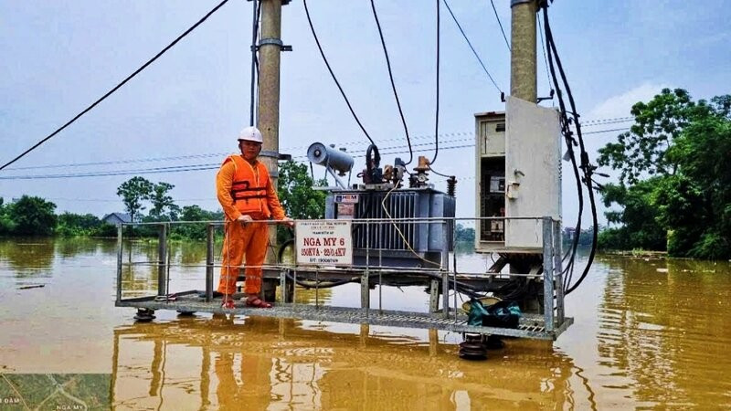 Cán bộ kỹ thuật trực tiếp kiểm tra trạm biến áp bị cô lập trong nước lũ nhằm bảo đảm an toàn lưới điện.