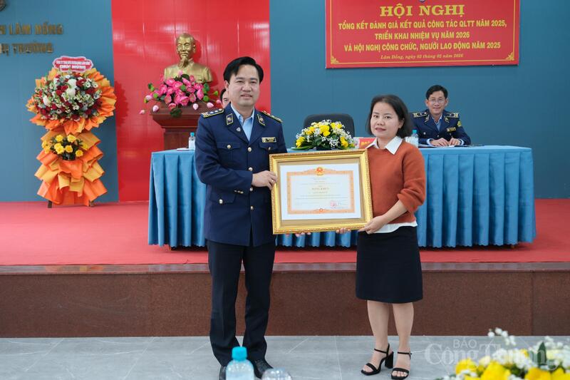 Ông Phan Văn Tuyên thay mặt hội nghị trao bằng khen của Thủ tướng Chính phủ cho bà Nguyễn Thị Bích Vân, chuyên viên Chi cục Quản lý thị trường tỉnh Lâm Đồng. Ảnh: Lê Sơn