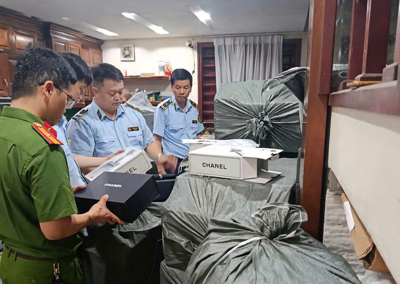 Lực lượng chức năng kiểm tra, phát hiện số lượng lớn túi xách, ví có dấu hiệu giả mạo các nhãn hiệu nổi tiếng tại một cơ sở kinh doanh thuộc phường Từ Sơn. Ảnh: QLTTBN